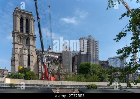 Notre Dame scaffolded, rebuilding after the fire, in front an excursion boat with tourists on the Seine, Paris, France Stock Photo