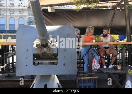 Customers relaxing in a outdoor cafe with a old naval gun decorated the waterfront of Puerto Madero.Buenos Aires.Argentina Stock Photo