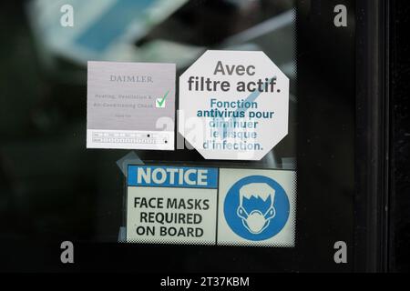 Strasbourg, France - Nov 22, 2023: A coach bus window displays multiple notices, including a Daimler HVAC check card, a face mask requirement sign, and an active antivirus filter sticker in French Stock Photo