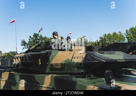 16.08.2023 Warsaw, Poland. Polish male tank crew during an open-air military parade in Warsaw. Side view of modern military tank and two soldiers peeking out od it. High quality photo Stock Photo