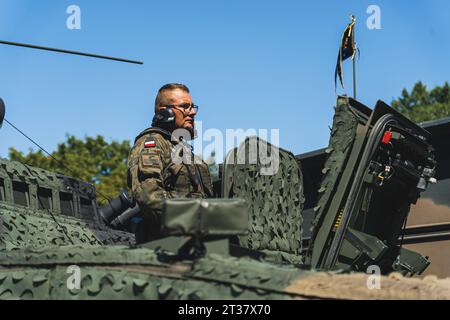 16.08.2023 Warsaw, Poland. Focused Polish male tank crew member standing in the tank door and looking at surrounding area. Blue sky. High quality photo Stock Photo