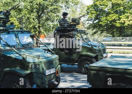 16.08.2023 Warsaw, Poland. Dark-green smaller military vehicles with armed soldiers on top riding through the streets of Warsaw during a military parade. High quality photo Stock Photo