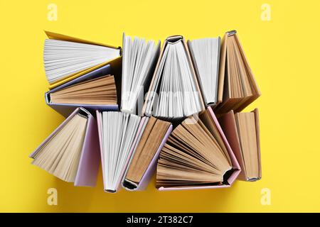 Many half open books on yellow background Stock Photo