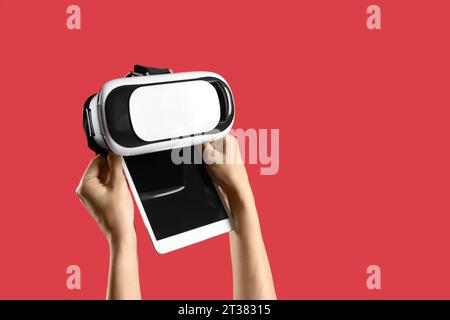Woman with blank tablet computer and VR glasses on red background Stock Photo