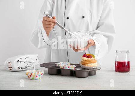 Female confectioner cooking tasty cakes on white background Stock Photo