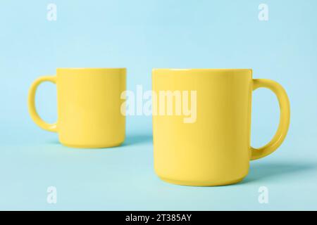 Two yellow ceramic mugs on light blue background Stock Photo