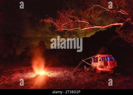 Toyota Coaster motorhome bushcamping with a campfire on under a starry sky, Kalgan Pool, Pilbara, Western Australia, Australia Stock Photo