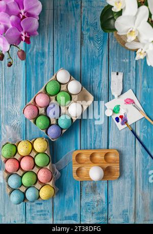 Multicolored easter eggs on blue table with paint brushes and paint Stock Photo