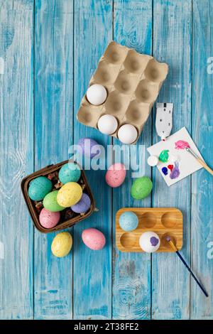 Multiple multicolored easter eggs, painting an egg purple with paint brush Stock Photo