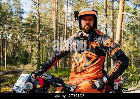 REPUBLIC OF KARELIA, RUSSIA - CIRCA JUNE, 2022: Off-road tournament Ladoga Trophy 2022 in Karelia. Portrait of a motorcycle racer in a helmet sitting on a sports motorcycle during a race Stock Photo