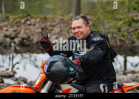 REPUBLIC OF KARELIA, RUSSIA - CIRCA JUNE, 2022: Off-road tournament Ladoga Trophy 2022 in Karelia. Portrait of a motorcycle racer in a helmet sitting on a sports motorcycle during a race Stock Photo