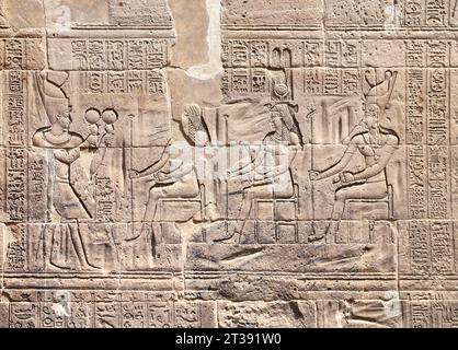 Ancient Egyptian bas-relief on stone wall. Figure of the pharaoh making ritual offerings to the goddess Isis. Temple of Isis on Agilkia Island (Philae Stock Photo
