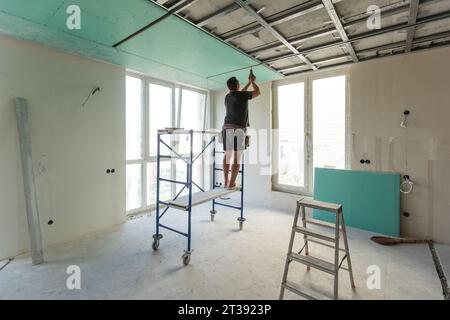 Man assembles profile metal frame for plasterboard ceilings Stock Photo