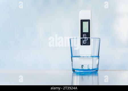 Electronic pH meter in a glass of water. TDS measurement of water. poor water quality, high values of salt impurities, copy space Stock Photo