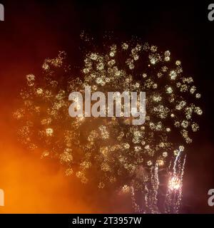 Looking up at exploding fireworks against a night sky Stock Photo