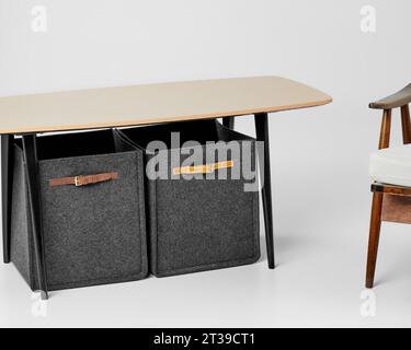 Two gray felt storage boxes with leather handles standing under table Stock Photo