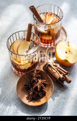 From above of fresh made apple cider cocktail with cinnamon sticks, anise star spice, and slices of apple served in a crystal glass with ice cubes on Stock Photo
