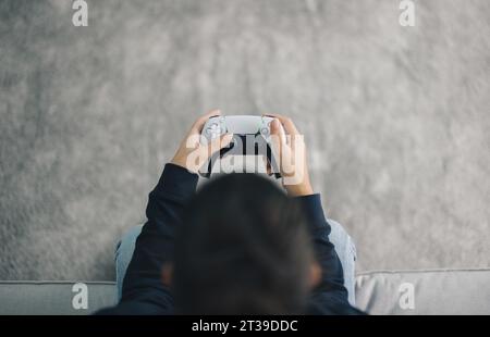 Top view of hands of anonymous female gamer using joystick while playing video game in living room at home during weekend Stock Photo