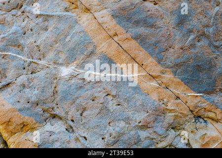 Close-up view of textured rock formations with a prominent white vein at Arnia Beach, Cantabria, Spain. Stock Photo