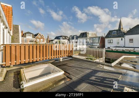 Empty rooftop with railing and residential buildings in the background under blue sky during sunny day Stock Photo
