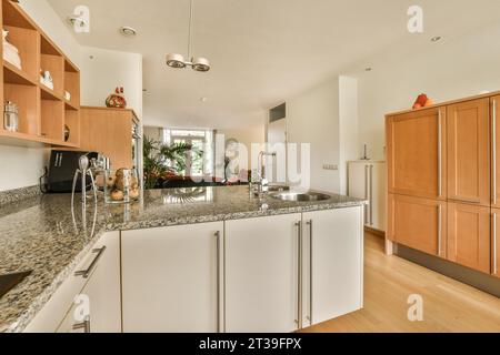 Modern kitchen with white cabinets and granite countertop at modern spacious home with light walls Stock Photo