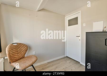 Brown leather chair and black wardrobe in small room with white walls and closed door in modern apartment Stock Photo
