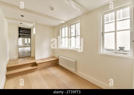 Empty living room with parquet floor and door leading to different room in new spacious apartment with white walls Stock Photo