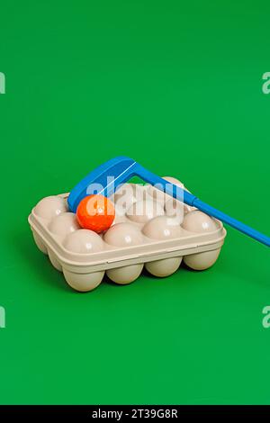 From above of different colored golf balls and plastic box with blue golf stick placed on green surface background of playground outside on sunny day Stock Photo