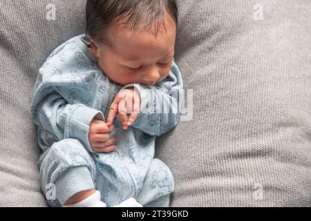 Top view of adorable infant baby lying on soft blanket with crossed legs and arms while sleeping Stock Photo