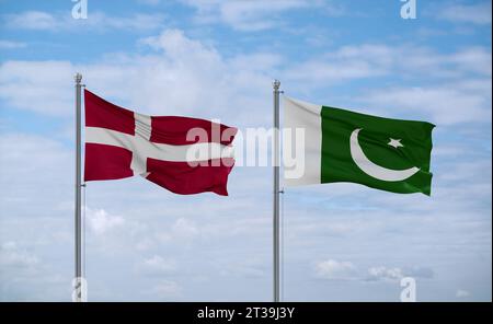 Pakistan and Denmark flags waving together on blue cloudy sky, two country relationship concept Stock Photo