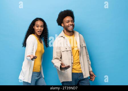 Happy smiling Afro African American couple standing with open hand gesture in light blue studio isolated background Stock Photo