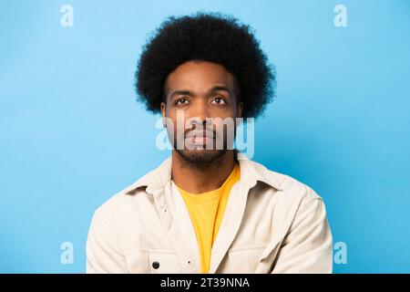 Afro African American man thinking and looking up in light blue color isolated studio background Stock Photo