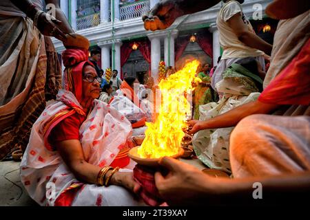 Kolkata, India. 22nd Oct, 2023. An Indian Hindu woman sits with burning fire pots on her hands and head as part of their ritual practice which includes blind faith and superstition to overcome every difficulties in coming future during the Maha ashtami celebration on the 8th day of Durga puja. Durga puja is the biggest Hindu festival running for 9 days all over India. (Photo by Avishek Das/SOPA Images/Sipa USA) Credit: Sipa USA/Alamy Live News Stock Photo