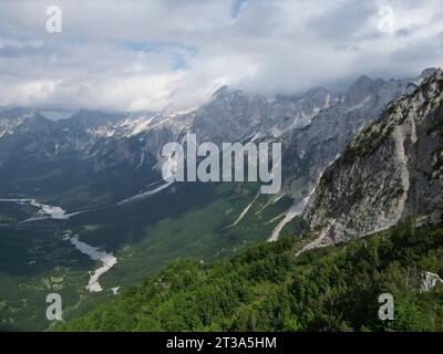 panoramic landscape view with snowy mountains, forests, valley and stony riverbeds in Albanian alps Stock Photo