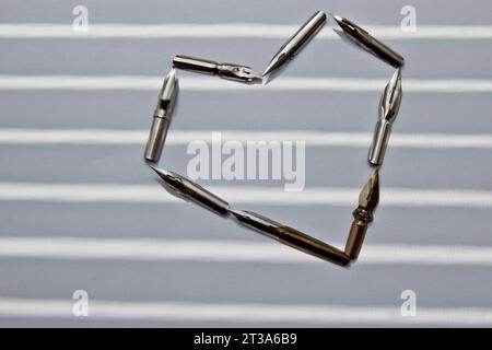 metal tips for the ink pen on a white background in solar rays. stationery on white desk close up top view. spelling lessons and caligraphy exercises. Stock Photo