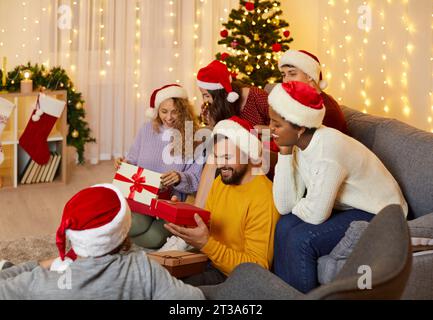 Happy family and friends having fun exchanging gifts during Christmas celebration at home. Stock Photo