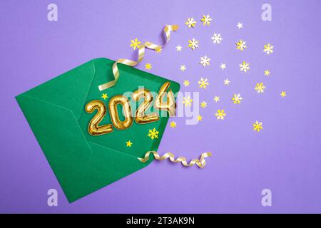 Golden balloons 2024 number emerging from a green envelope with yellow star shaped confetti Stock Photo