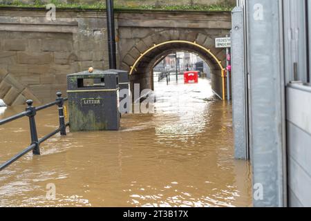 Bewdley, UK. 23rd October, 2023. Bewdley after Storm Babet. River levels remain very high and the flood barriers are still in place as large areas are engulfed by the swollen River Severn. Water flows freely under the bridge pedestrian underpass. Credit: Lee Hudson Stock Photo