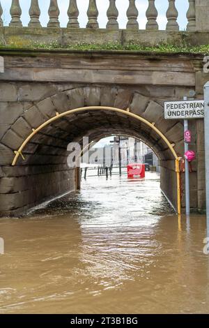 Bewdley, UK. 23rd October, 2023. Bewdley after Storm Babet. River levels remain very high and the flood barriers are still in place as large areas are engulfed by the swollen River Severn. Water flows freely under the bridge pedestrian underpass. Credit: Lee Hudson Stock Photo
