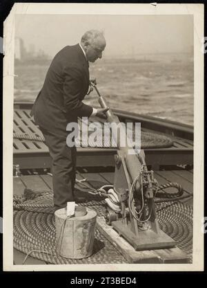 Photo of Max Rindskopf and His Life Saving Gun A Gun to Save; Not to Kill! New Item Max Rinskoff, Inventor, on the New York City Police Boat 'Hylan' Demonstrating How His G-0 Life Line Hurling Gun Works. The Gun Shoots a Life Line Accurately 1,400 Feet and Has the Highest Commendation of the U.S. Stealboat Inspection Board. The Powder Used in Inclosed in an Air and Water-Tight Cartridge and the Gun is Said Never to Mis-Fire and to Have Very Little Recoil. Stock Photo