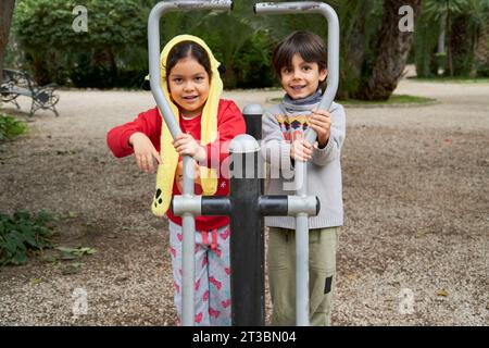 Multiethnic children with Christmas sweaters looking at camera while playing at the park Stock Photo