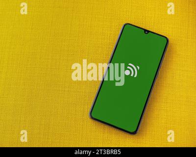Lod, Israel - July 16,2023: Unified Remote app launch screen on smartphone on yellow fabric background. Top view flat lay with copy space. Stock Photo