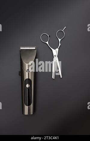 Hair clipper and Hairdresser scissors on black background. Mens hairdressing desktop with tools for shaving top view. Male haircut, fashion. Hairdress Stock Photo