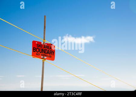 Ski area boundary sign against a blue sky and a puffy cloud Stock Photo