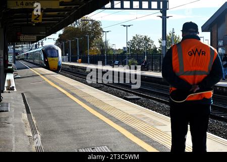 Train departing from station with GWR guard standing watching, UK Stock Photo