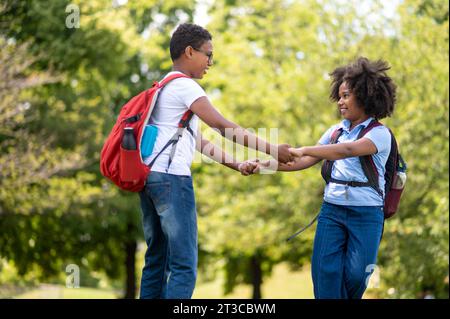 Smiling boy and girl walking hand in hand in the park Stock Photo