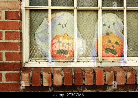 Pumpkins, jack-o-lanterns & ghosts look out the old window in brick building for Halloween building scene. The image shows carved faces and spooks. Stock Photo