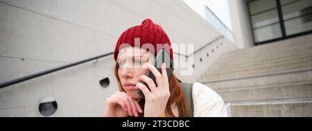 Portrait of worried girl calls somebody with concerned face, being on a phone, receives bad news, looking upset by conversation on smartphone Stock Photo