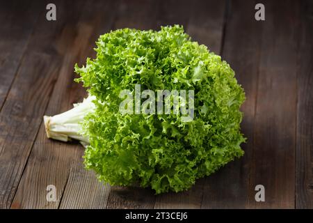 Big bunch of fresh green lettuce leaves on a wooden background. Healthy food, source of minerals and vitamins. Stock Photo