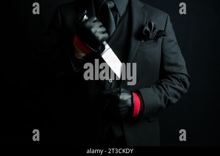 Portrait of Mysterious Man in Black Suit Pulling Knife Out of Jacket. Mafia Hitman or Gangster Stock Photo